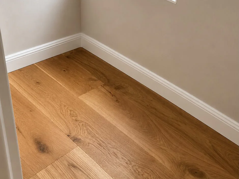 Detail van de eiken parketvloer in de hoek, strak afgewerkt tegen de plint